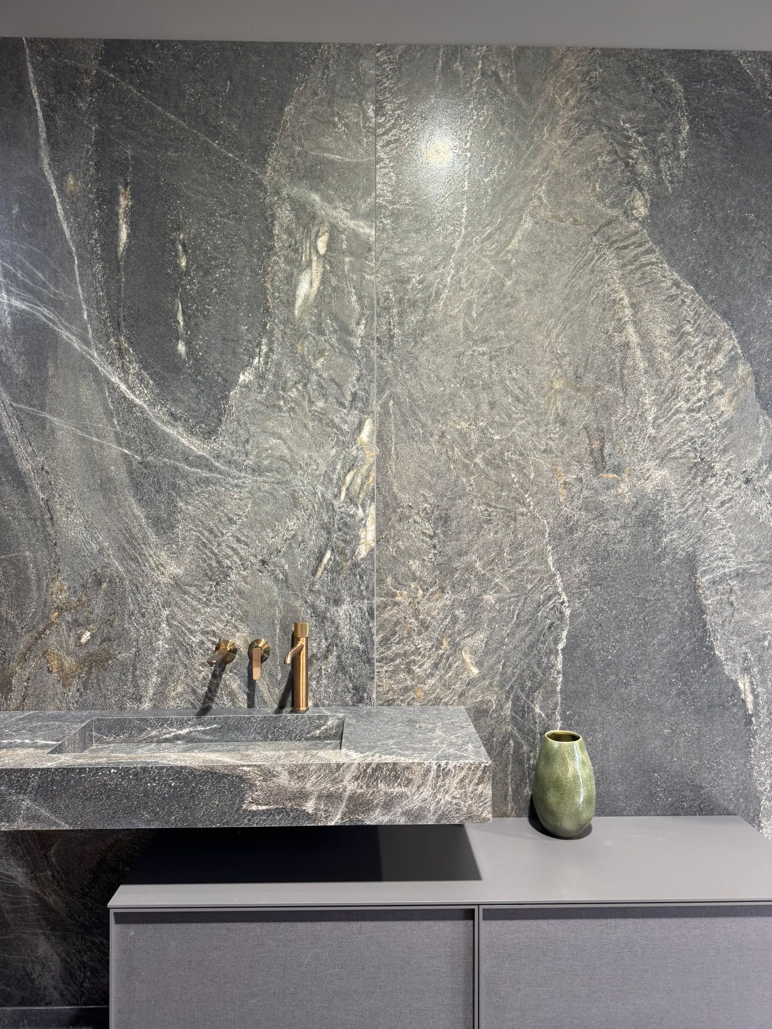Dunkle Natursteinwand mit Armatur im Premium-Bad